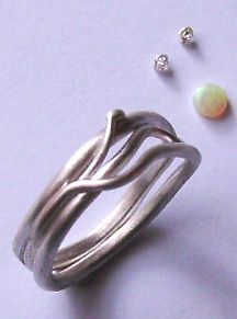 sinuous ring design next to an opal and two diamonds